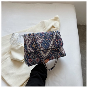 Detail of blue geometric woven pattern and golden chain strap on ethnic style tote bag