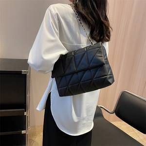 Borsa a tracolla nera trapuntata con motivi geometrici indossata da una modella