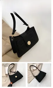 Detail view of a black felt baguette bag with a circular gold metal magnetic buckle