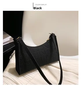 Detail of black felt underarm bag with geometric embossed texture and gold metal hardware