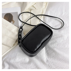 Detail of black crossbody bag with embossed lettering and thick chain strap decoration