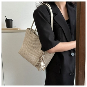 Gros plan d'un sac cabas en paille avec foulard en soie porté par un mannequin