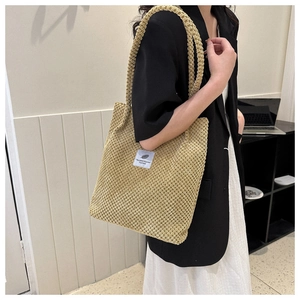 Detail of beige bubble knit tote bag with a woven brand patch and soft texture