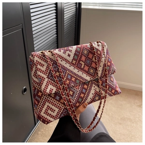 Detailed shot of ethnic woven pattern on a crossbody bag with gold chain strap