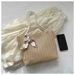 Détail d'un sac cabas en paille tissé main avec anses en corde et décoration de foulard