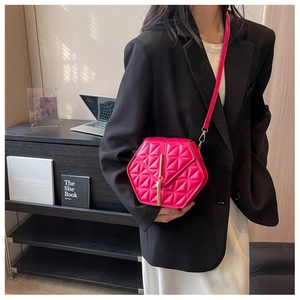 Detail showing fuchsia hexagonal quilted handbag with golden tassel buckle on model