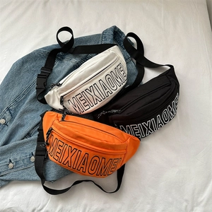 Drei Harajuku-Hüfttaschen in Weiß, Schwarz und Orange auf einer Jeansjacke liegend