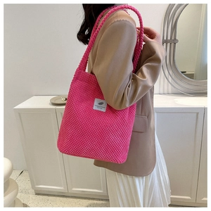 Detailed view of the fuchsia corduroy tote bag worn over the shoulder by a model