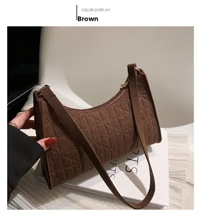 Close-up of brown felt underarm bag with embossed heart texture and gold zipper detail