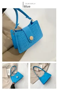 Detail view of blue crocodile embossed baguette bag with unique circular wooden button