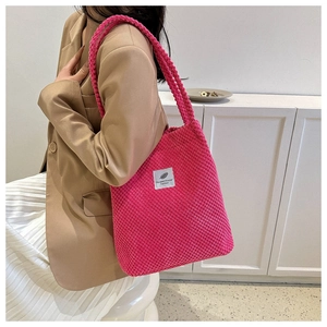 Close-up of rose red corduroy tote bag with woven texture and white feather logo patch