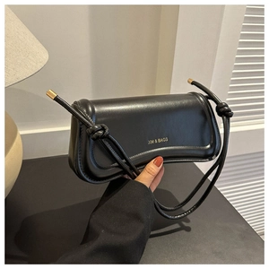 Detail of minimalist black rectangle shoulder bag with knotted cord strap and gold logo