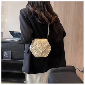 Close-up of beige quilted crossbody bag with golden tassel detail worn by a model