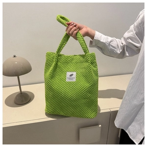 Detail of bright green popcorn textured knit handbag featuring a stitched white label