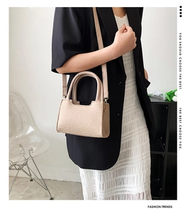 Detail of a beige felt crossbody bag paired with a black blazer and white dress on a model