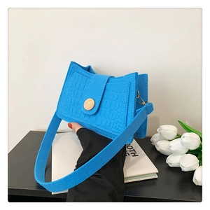 Detail of blue faux crocodile texture on a stylish felt shoulder bag with a wooden button