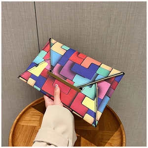Macro view of colorful geometric block pattern and gold metal clasp on a clutch bag