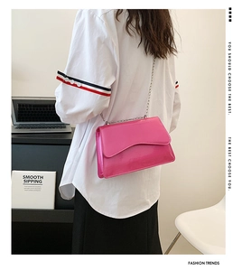 Detail view of pink patent leather shoulder bag with wavy flap and silver chain strap