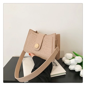 Detail of crocodile embossed cream felt bag with wooden buckle and wide shoulder strap