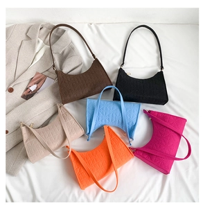 Flat lay of six colorful felt shoulder bags with floral embossing on a soft background