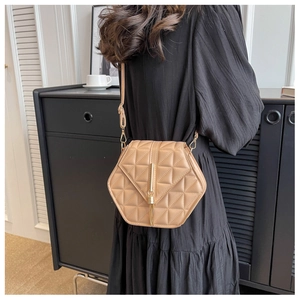 Detail of beige geometric crossbody bag with quilted texture and gold tassel hardware