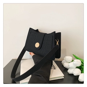 Close-up of black crocodile pattern shoulder bag with a stylish wooden button closure