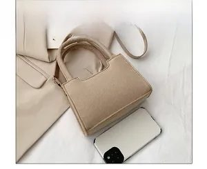 Mini felt crossbody bag in beige compared with a smartphone for precise scale and size