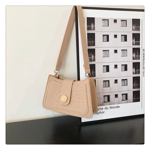 Close-up of beige crocodile pattern underarm bag with decorative wooden buckle and strap