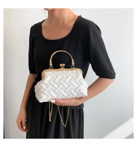 Detailed view of woven satin evening bag with round gold handle and metal chain strap