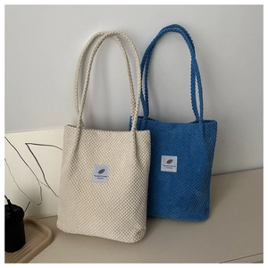 Detail of corduroy tote bags in cream and royal blue with feather patch decoration