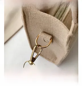 Detailed close-up of golden D-ring and lobster clasp on high-quality felt shoulder bag