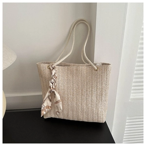 Détail d'un sac cabas tissé avec poignées en corde et foulard en soie décoratif