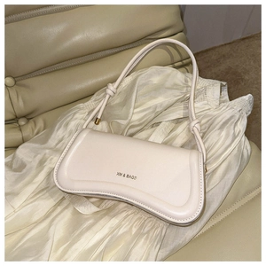 Detail of cream leather shoulder bag featuring knotted strap and XM & BAGS logo