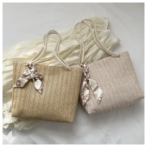 Détail de sacs en paille tissée avec poignées en coton et foulard en soie imprimé décoratif