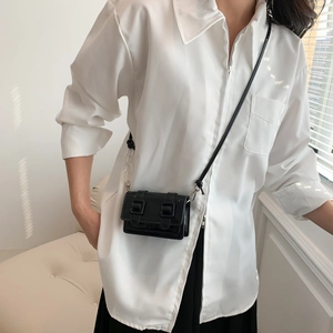 Mini black patent leather Cambridge crossbody bag with dual buckles on white shirt