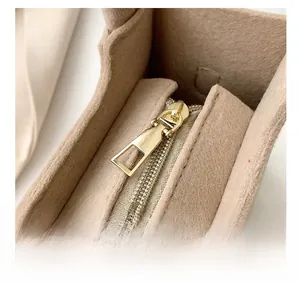 Macro detail of high-quality gold zipper hardware on a minimalist brown felt handbag
