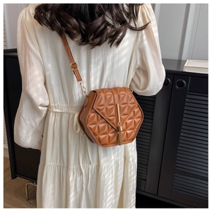 Detail of brown hexagonal crossbody bag with quilted rhombus pattern and gold tassel charm