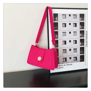 Close-up of bright pink faux crocodile shoulder bag with golden round buckle and wide strap