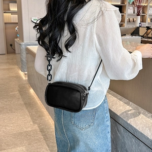 Minimalist black crossbody bag with double chain strap and stylish leather texture