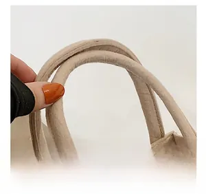 Macro view of beige felt tote bag showing comfortable thick handle and material detail