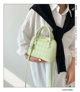 Model wearing a mint green quilted shell bag with gold hardware and shoulder strap