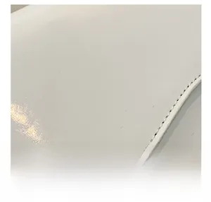 Close-up of white leather texture with black stitching detail on small square bag