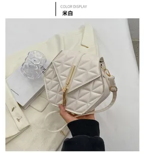 Detail of beige quilted hexagonal crossbody bag with gold tassel and PU leather texture