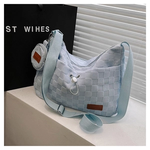 Detail view of light blue woven crossbody bag with matching round coin purse and wide strap