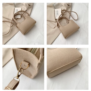 Close-up of oatmeal felt handbag with gold hardware zippers and adjustable straps