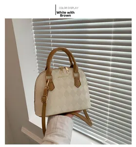 Detail of a quilted shell bag in white and brown with gold logo and zipper hardware