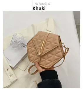Khaki quilted hexagonal crossbody bag with gold tassel detail on a white blazer