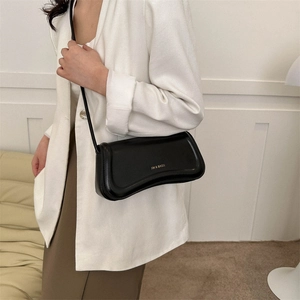 Minimalist black leather underarm shoulder bag worn with a white professional blazer