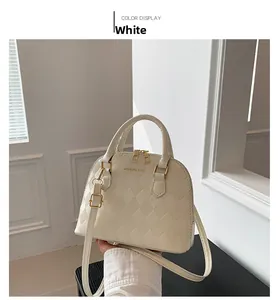 Detail of white shell-shaped bag with diamond quilted texture and gold dual zipper