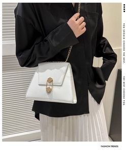 Détail d'un sac à bandoulière blanc en cuir avec chaîne dorée et fermoir hexagonal